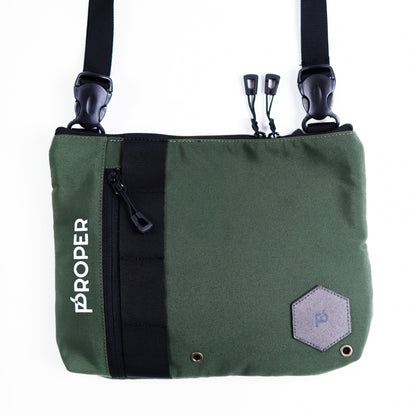 A green color proper compact sling bag with multiple compartments and a zippered back pocket, featuring a white brand logo on the front.