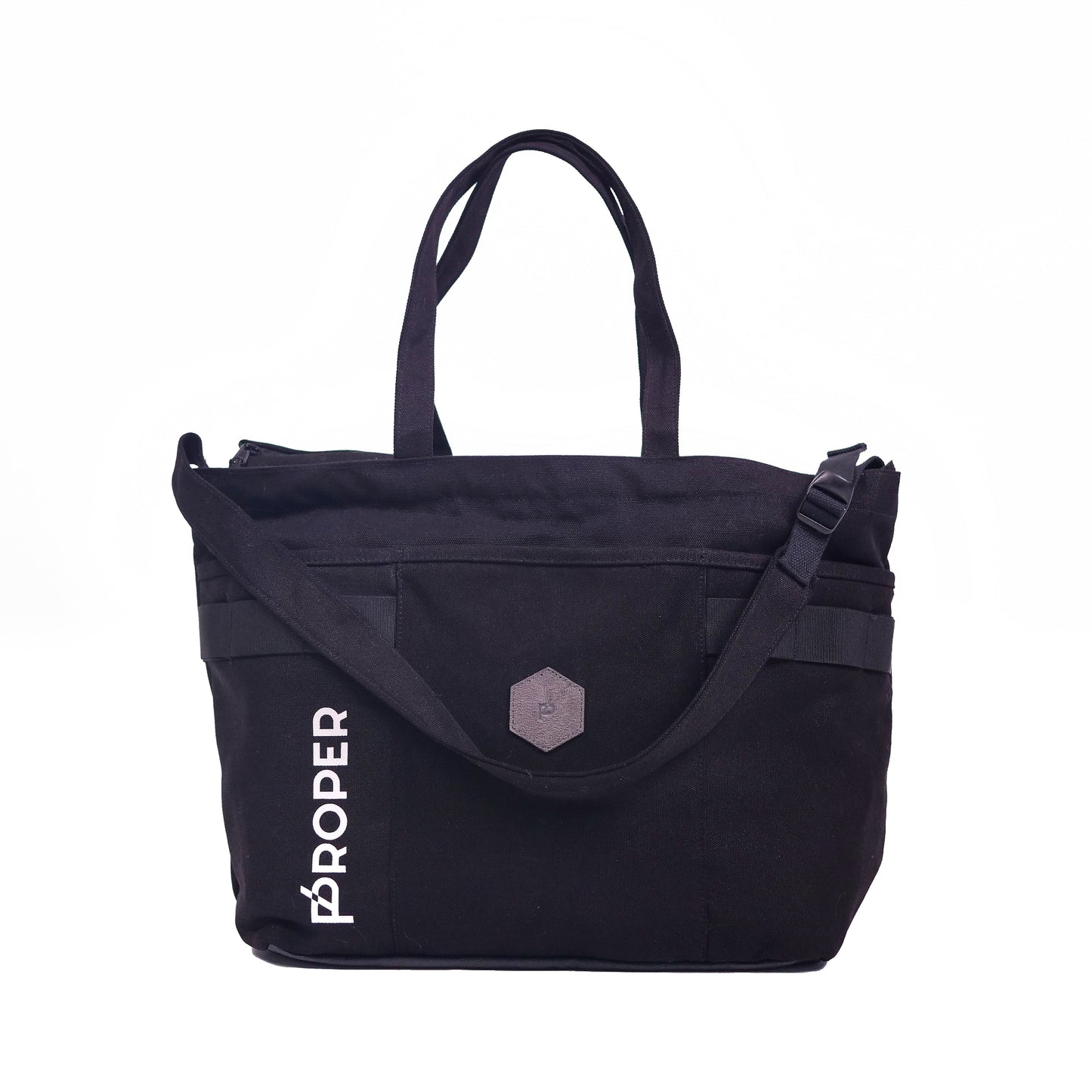 A black tote bag with the text 'PROPER' on the side, featuring a large main compartment, a front pocket, and adjustable straps.